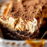 A square plate of millionaire’s tiramisu elegantly layered with rich cream and dusted cocoa, styled on a white marble surface with a minimalist and sophisticated touch.